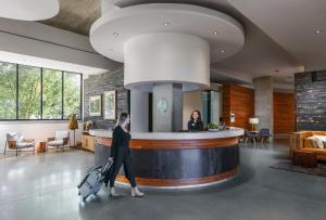 a woman walking through a lobby with her luggage at Hotel Indigo Athens - University Area by IHG in Athens