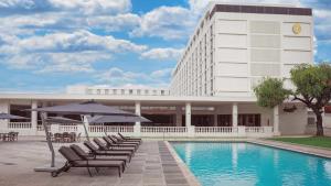 a hotel with chairs and an umbrella next to a pool at Holiday Inn - Lusaka by IHG in Lusaka