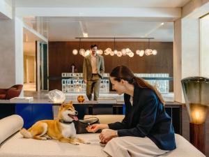 a woman sitting on a couch with a dog at Fairmont Golden Prague in Prague