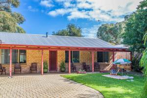 a yellow brick house with a patio in the yard at Waves And Moore - Beautifully presented home in Guilderton