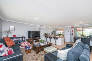 a living room with a blue couches and a kitchen at Waves And Moore - Beautifully presented home in Guilderton