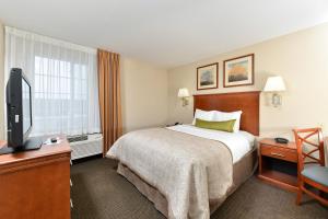 a hotel room with a bed and a flat screen tv at Candlewood Suites Chambersburg by IHG in Chambersburg