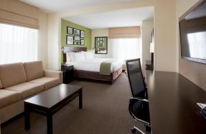a hotel room with a bed and a couch at Holiday Inn Express Hotel & Suites Rogers by IHG in Rogers