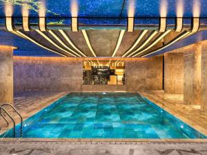 an indoor pool with blue water in a building at Mövenpick Hotel Istanbul Marmara Sea in Istanbul