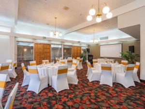 a conference room with white tables and chairs and a screen at Wairakei Resort Taupo in Taupo +265 photos