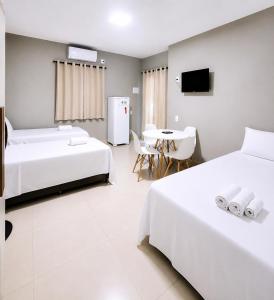 a bedroom with two beds and a table with a tv at Mar & Sol Preá - 700m da Praia - 12km de Jeri - 15km do Aeroporto in Prea