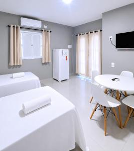 a room with two beds and a table and a refrigerator at Mar & Sol Preá - 700m da Praia - 12km de Jeri - 15km do Aeroporto in Prea