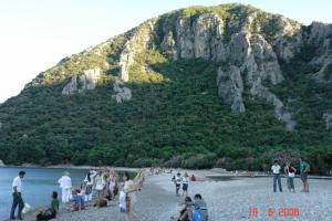 un grupo de personas en una playa con una montaña en el fondo en Korsan Pension, en Olympos