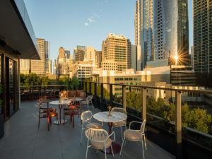a balcony with tables and chairs and a city skyline at Mercure Melbourne La Trobe Street in Melbourne