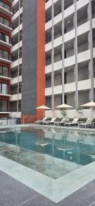 a swimming pool with chairs and umbrellas in front of a building at Apartment in downtown Zapopan in Guadalajara