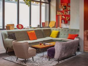 a living room with a couch with colorful pillows at Mercure Paris Centre Gare Montparnasse in Paris