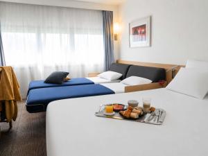 a hotel room with two beds and a tray of food at Novotel Nantes Centre Gare in Nantes