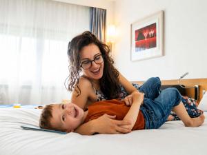 a woman and a boy laying on a bed at Novotel Nantes Centre Gare in Nantes +43 photos
