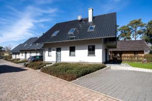 a white house with a black roof and a driveway at Strandhaus-3-EG in Marienfelde