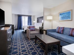 a hotel room with a couch and a bed and a tv at Garner Hotel Longview South by IHG in Longview