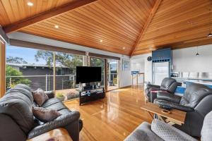 a living room with leather furniture and a flat screen tv at Blue Water - BYO Linen in Anglesea
