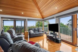 a living room with leather furniture and a flat screen tv at Blue Water - BYO Linen in Anglesea