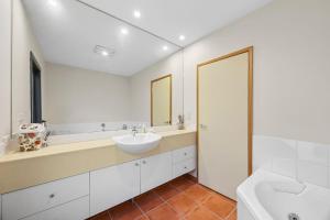 a white bathroom with a sink and a tub at Blue Water - BYO Linen in Anglesea