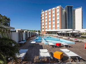 a swimming pool with lounge chairs and a hotel at Novotel Salerno Est Arechi in Salerno
