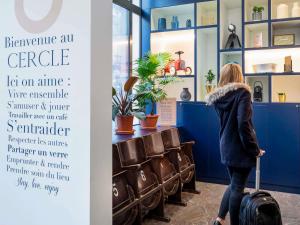 a woman with a suitcase standing in a waiting room at Aparthotel Adagio Paris Haussmann Champs Elysées in Paris +39 photos