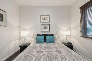 a white bedroom with a bed with blue pillows at Aireys Oasis in Aireys Inlet