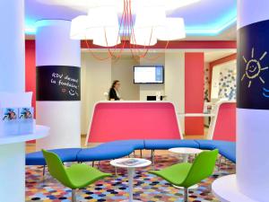 a room with colorful chairs and a table and a person at ibis Styles Montelimar Centre in Montélimar
