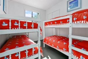 a bedroom with two bunk beds with red sheets at Mirimar in Apollo Bay