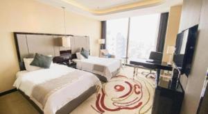a hotel room with two beds and a desk and a television at Pacific Regency Hotel Shenyang in Shenyang