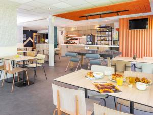a restaurant with tables and chairs with food on them at ibis budget Bourg en Bresse in Bourg-en-Bresse