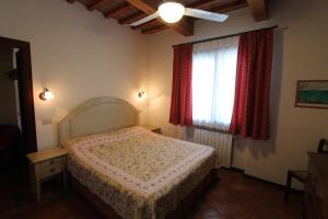 CollemezzanoにあるAppartamenti Brunettiのベッドルーム1室(ベッド1台付)、赤いカーテン付きの窓が備わります。