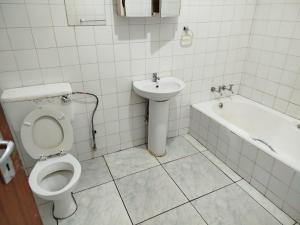 a bathroom with a toilet and a sink and a bath tub at Manor Rentals in Potchefstroom