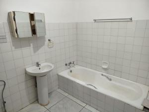 a bathroom with a sink and a tub and a mirror at Manor Rentals in Potchefstroom