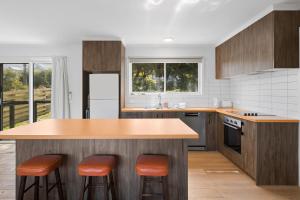 a kitchen with a island with orange bar stools at Myrtle Cottage in Aireys Inlet