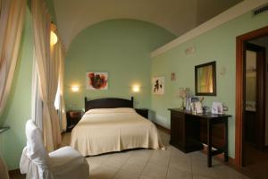 1 dormitorio con cama, mesa y espejo en Hotel Il Duomo, en Oristano