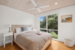 a bedroom with a bed with a ceiling fan and a window at Coastwalk in Aireys Inlet