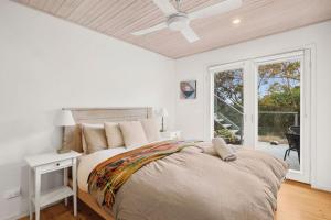 a white bedroom with a bed and a window at Coastwalk in Aireys Inlet +9 photos