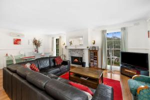a living room with a leather couch and a fireplace at Noble Villa - BYO Linen in Anglesea