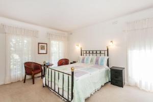 a white bedroom with a bed and two chairs at Noble Villa - BYO Linen in Anglesea