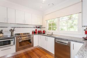 a kitchen with white cabinets and stainless steel appliances at Noble Villa - BYO Linen in Anglesea