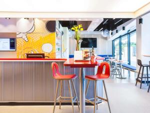 a restaurant with red bar stools at a counter at Ibis Styles Mulhouse Centre Gare in Mulhouse