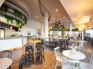 a restaurant with tables and chairs and a bar at Novotel Surfers Paradise in Gold Coast