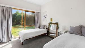 a bedroom with two beds and a large window at Ocean Ridge House Fairhaven in Aireys Inlet