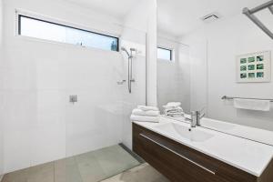 a white bathroom with a sink and a shower at Drift - Luxury, location and ocean views in Wye River