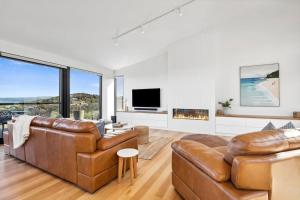 a living room with two leather couches and a tv at Hakea Ridge in Aireys Inlet