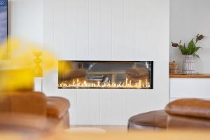 a fireplace in a living room with flames in it at Hakea Ridge in Aireys Inlet