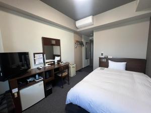 a hotel room with a bed and a desk and a television at Hotel Route-Inn Tokuyama Ekimae in Shunan