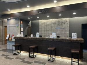 a hotel reception counter with stools in a lobby at Hotel Route-Inn Tokuyama Ekimae in Shunan +23 photos