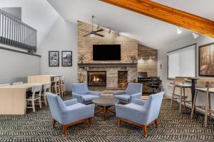 a lobby with a fireplace and chairs and a tv at AmericInn by Wyndham Sauk Centre in Sauk Centre