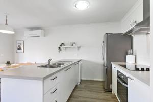 a kitchen with white cabinets and a stainless steel refrigerator at Merihaven in Apollo Bay