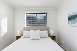 a white bedroom with a large bed and a window at Merihaven in Apollo Bay +7 photos